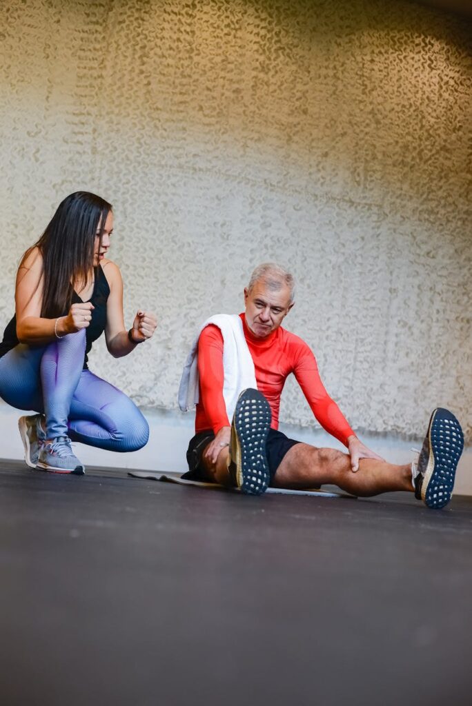 an elderly man listening to his trainer while sitting on the floor